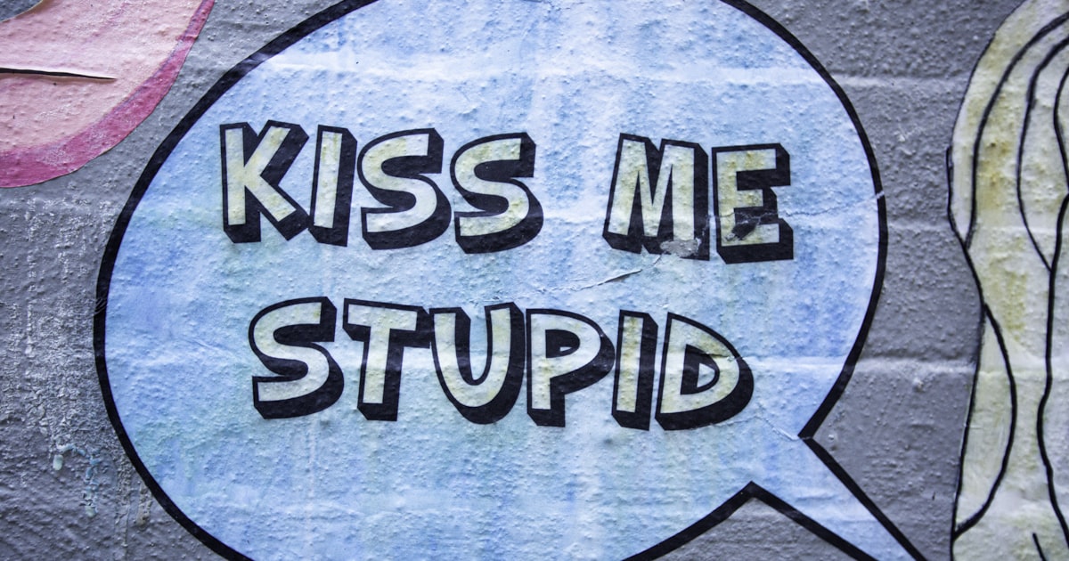Graffiti speech bubble with "kiss me stupid" text.