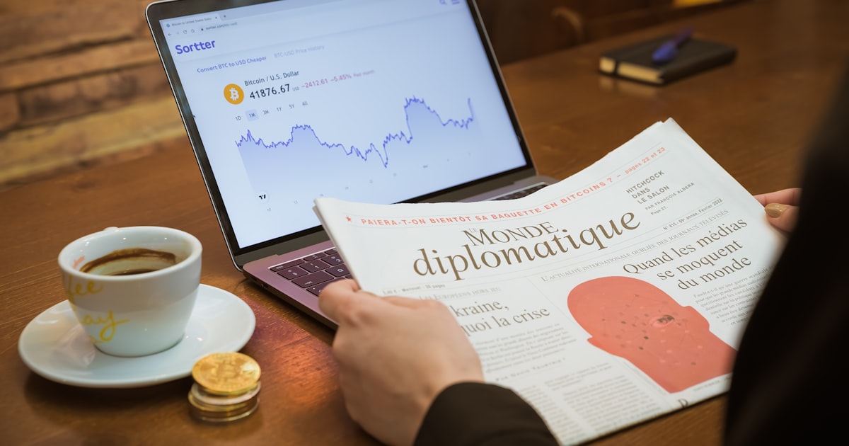 a person sitting at a table with a laptop and a cup of coffee