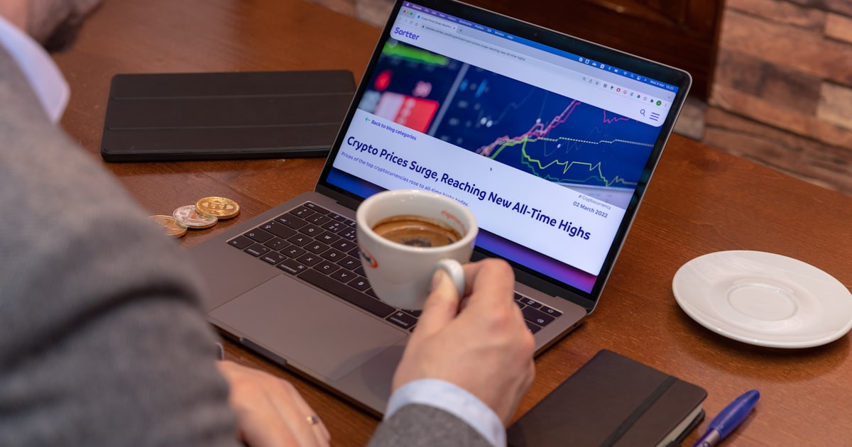 a man sitting at a table with a laptop and a cup of coffee